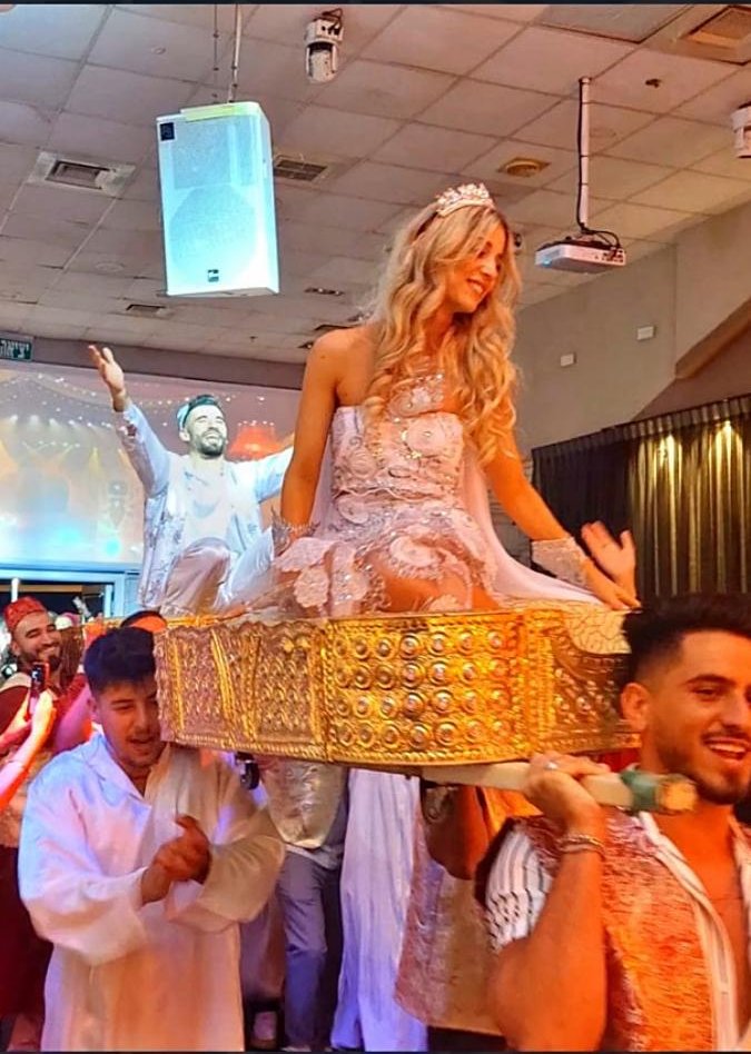 כלה מורמת על אפריון מוזהב בכניסה לחינה